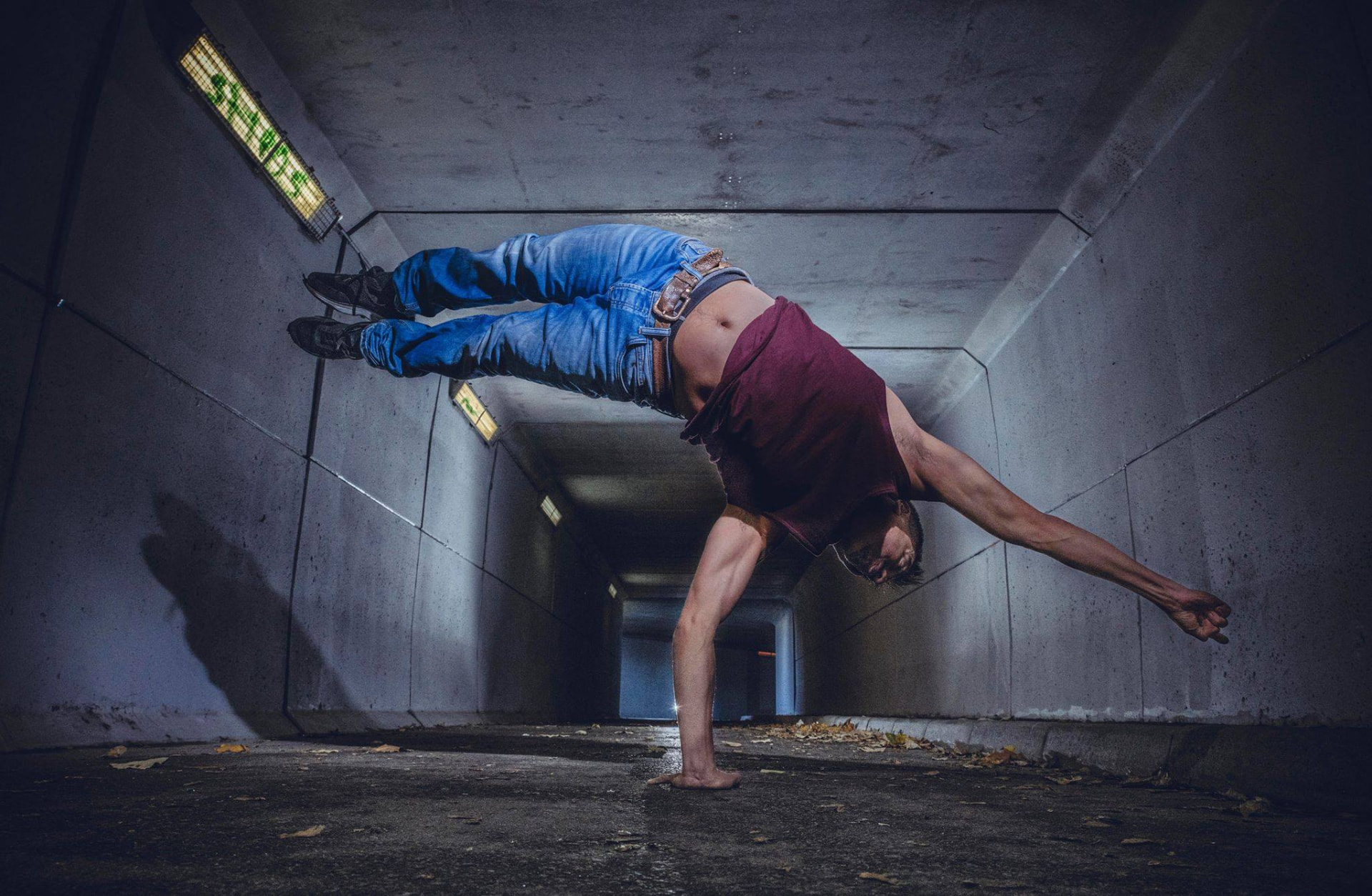 En danser balanserer på én hånd i en betongtunnel