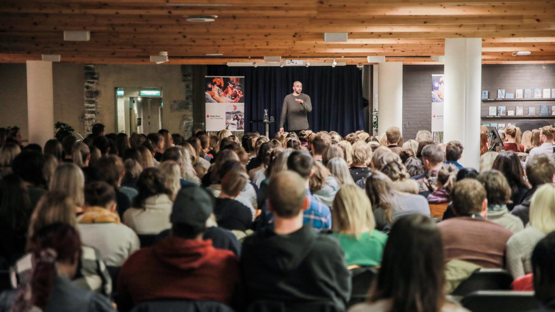 En mann holder foredrag foran et fullsatt publikum i en sal